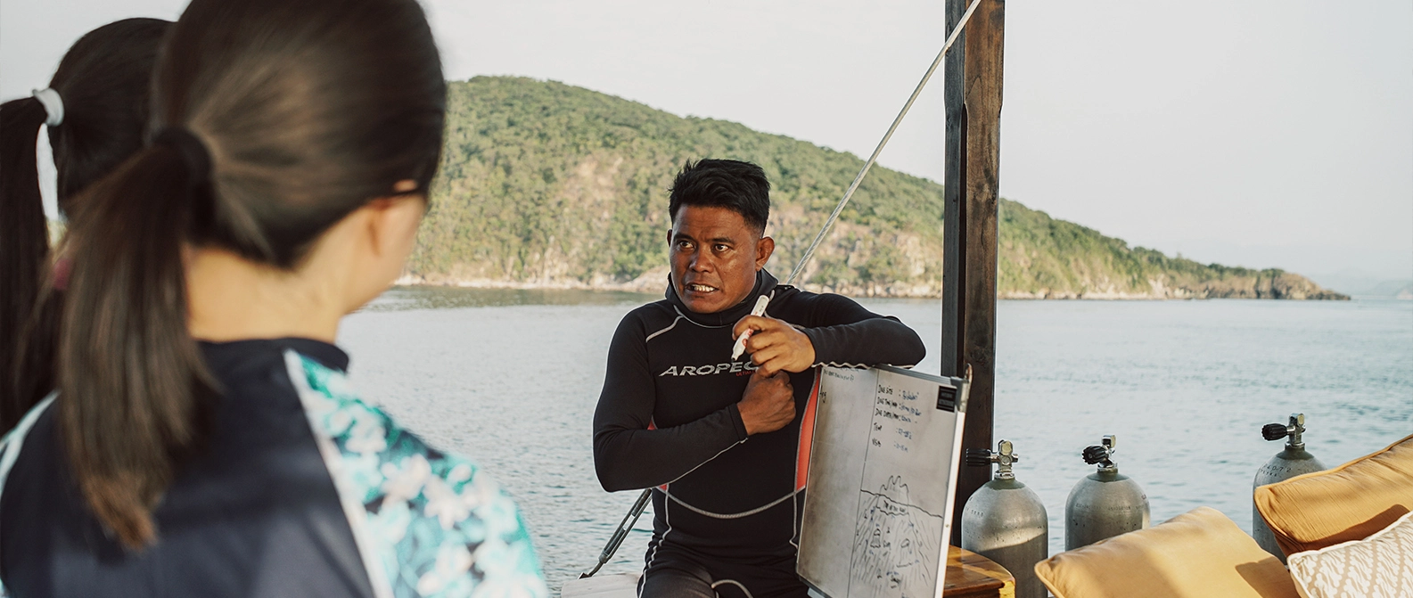Boat crew showing passengers how to use life jackets on deck